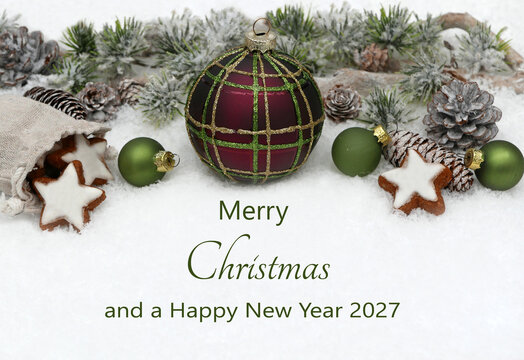 Christmas card: Christmas decoration with fir branches and Christmas baubles. The text "Merry Christmas and a Happy New Year 2027" appears in the snow.