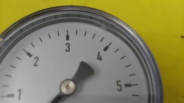 Macro pan shot of a round mechanical pressure gauge dial indicator with a black needle