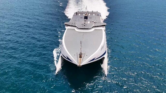 Aerial drone cinematic video of Champion Jet 1 high speed passenger catamaran ferry, reaching port of Santorini island, Cyclades, Greece