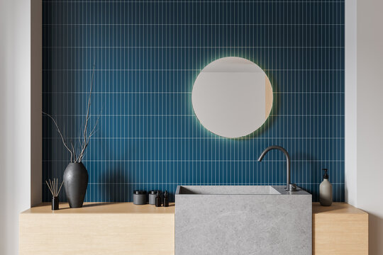 Modern bathroom interior with minimalist sink, round mirror, blue tile wall, wood counter and stylish decor elements. 3D Rendering