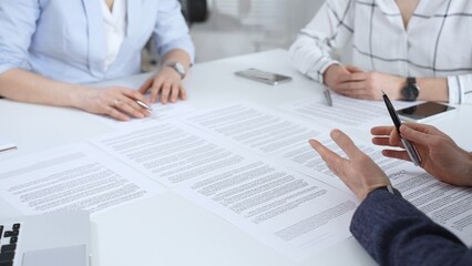 Business partners discussing legal contracts and partnership agreements, reviewing terms,...