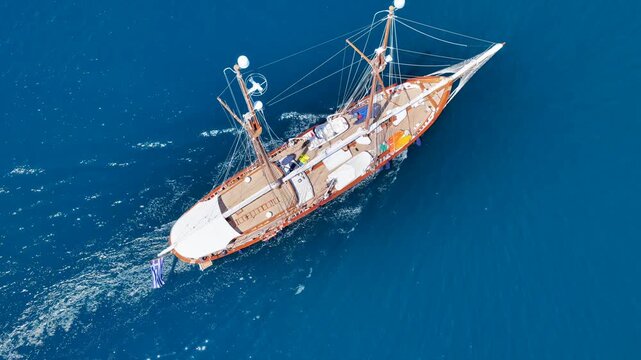 Aerial drone cinematic video of classic sailing wooden ship cruising in low speed near marina and port of Zea or Pasalimani, Piraeus, Attica, Greece