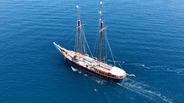 Aerial drone cinematic video of classic sailing wooden ship cruising in low speed near marina and port of Zea or Pasalimani, Piraeus, Attica, Greece