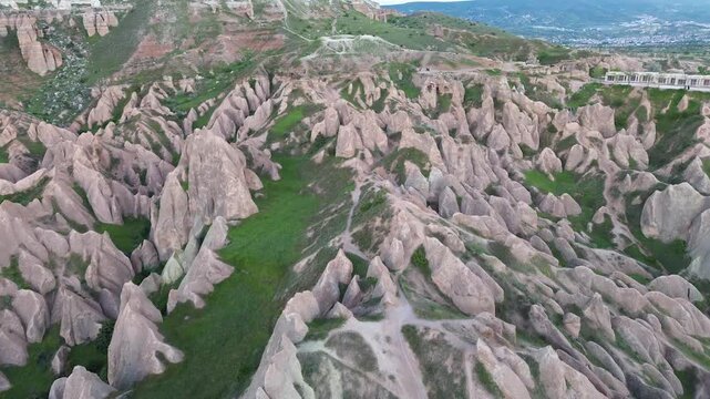 4K drone footage glides low over Red Valley's volcanic rock formations in Cappadocia at sunset, highlighting warm ancient stone tones in soft natural light. Completely raw, unedited footage