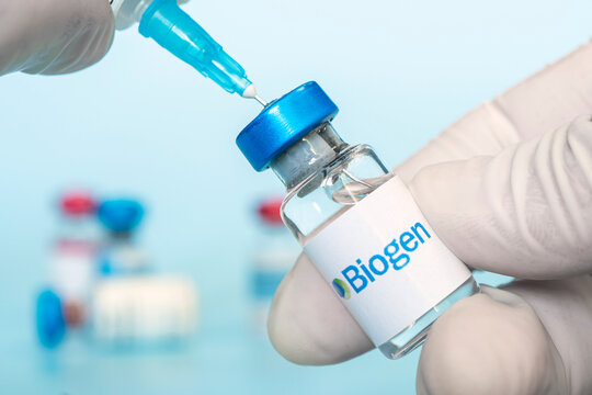 Vials of liquid on a white table and the logo of a large pharmaceutical company.