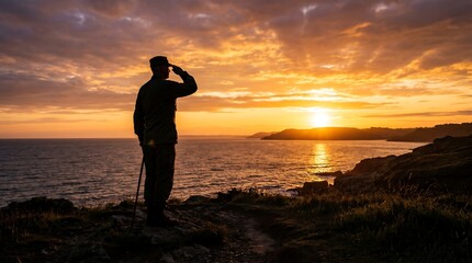 Fototapeta premium Silhouette of a saluting soldier standing on a cliff at sunset overlooking the ocean