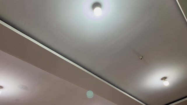Interior home lighting detail with glowing electric bulb on plasterboard ceiling