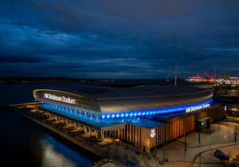 Naklejka premium Hill Dickinson Stadium in Liverpool, Merseyside, England at night. Modern football stadium illuminated after dark on the River Mersey waterfront, aerial view of a major sporting landmark.