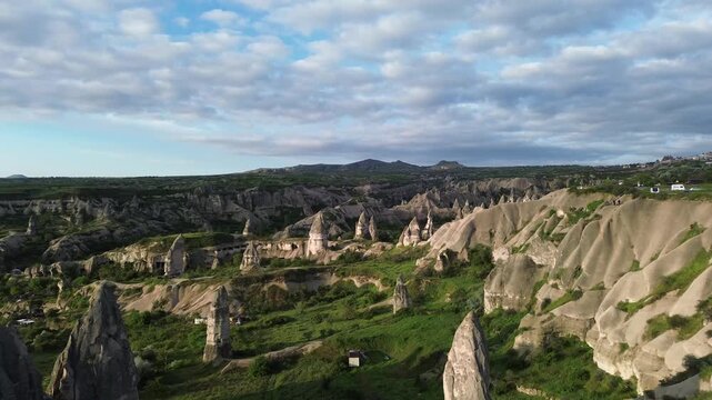 4K drone footage over Pigeon Valley, Cappadocia at sunrise. Golden dawn light illuminates ancient volcanic rocks carved with thousands of dovecotes &mdash; raw, unedited aerial footage.