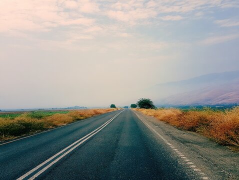 Scenic Countryside Road with Partly Cloudy Sky and Natural Vegetation