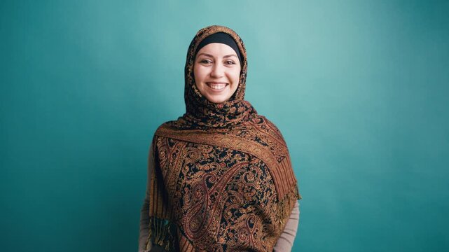 Portrait of a young, modern arab woman wearing a traditional headscarf. Happy and confident muslim girl smiling against a colored background