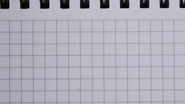 The sheets of a grid notebook are turned over, the background of the paper