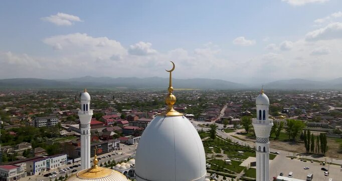 Cinematic aerial orbit shot of the main white dome with golden crescent of the Pride of Muslims mosque in Shali, Chechnya