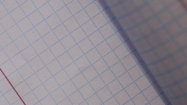 The sheets of a squared notebook are turned over, the background of the paper