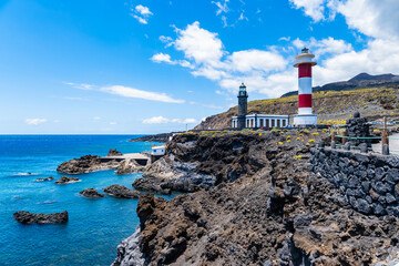 The red-and-white Fuencaliente lighthouse stands on a dark, rugged volcanic rock shoreline. La Palma, Canary Islands, Spain © pkazmierczak