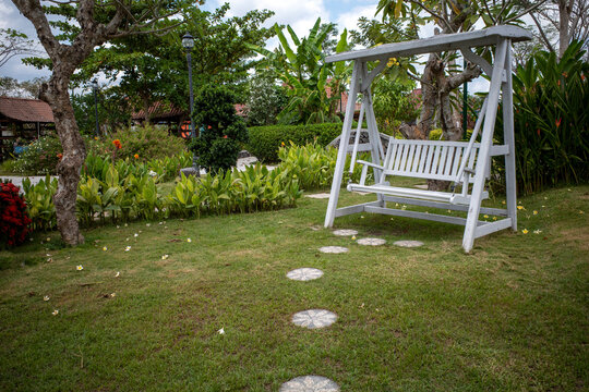 A white vintage metal benche in the green garden park