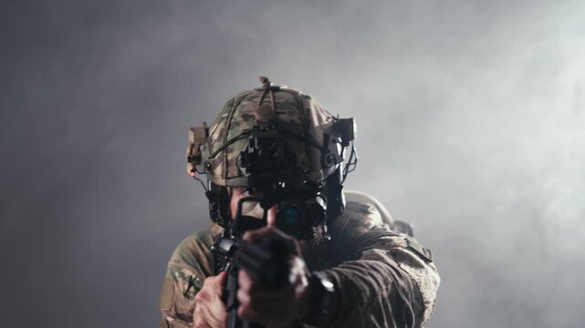 Military professional in combat equipment aiming weapon in smoke-filled setting. Concept armed forces, protection and tactical operations.
