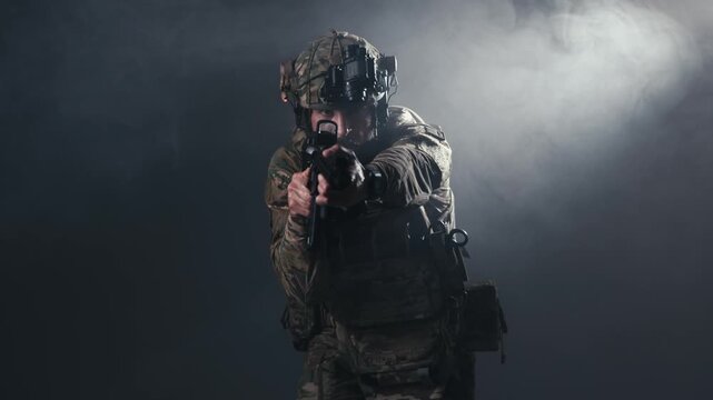 Fighter in contemporary combat equipment aims weapon forward, showcasing tactical stance and focus in a low-light environment with smoke effects enhancing the scene