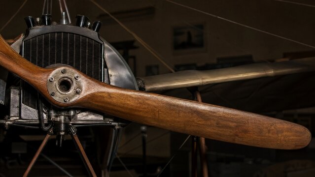 The wooden propeller of a vintage monoplane in a quiet hangar.