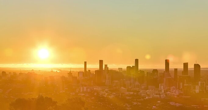 4k Locked down Time Lapse motion of sunrise of sun rising from the horizon into the clear morning sky with the Brisbane City CBD in foreground with the urban sprawl of Brisbane City, Brisbane, Queensl