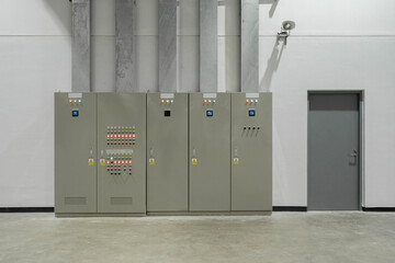 Fototapeta premium Modern industrial electrical control panel with switchgear, indicator lights, and grey door in a clean utility room.