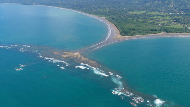 Aerial view of the iconic Uvita whale tail sand formation merging with the coastline during a low tide in Costa Rica