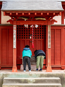 神社でお辞儀をして参拝する子供の後ろ姿
