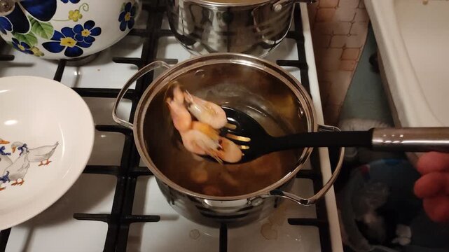 Removing cooked shrimp from pot with slotted spoon, first person view