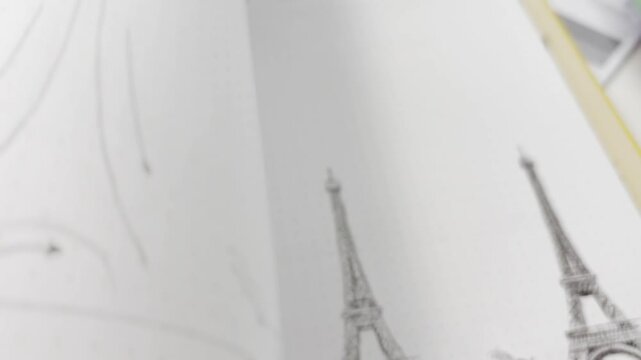 Close up of flipping through sketchbook pages showing pencil drawings of animals, landscapes, and the eiffel tower, highlighting creative process and artistic illustration