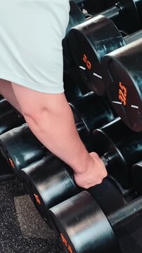 Bodybuilding in the gym - young sporty man performs training for arm