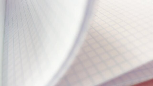 Turning pages of a squared paper notebook, revealing the handwritten text back to school at the end, symbolizing the concept of learning, studying, and education