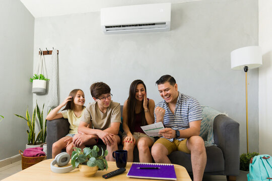 Happy family celebrating lower electricity bill thanks to efficient air conditioning, saving money during summer heat