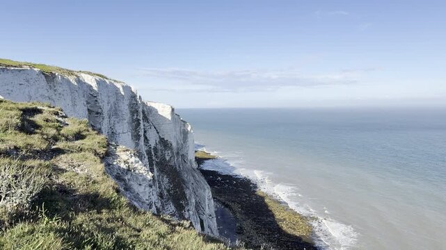 Grassy cliff edge overlooking coastal shoreline panning