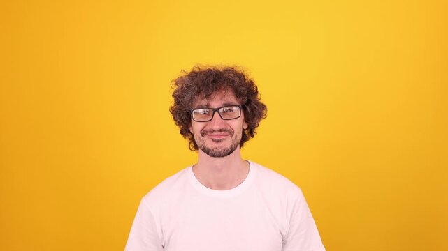 Person pointing upward with both index fingers, directing attention to empty space above in a bright yellow studio portrait.