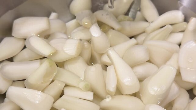 白い宝石と呼ばれるらっきょう。食用。らっきょうを洗うためにボウルに水を注いでる動画。