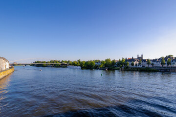 Obraz premium Spring cityscape, Architecture traditional houses and Churches on the riverside under blue sky, The Hoge Brug pedestrian and cycle bridge crossing the Meuse river in Maastricht, Limburg, Netherlands.