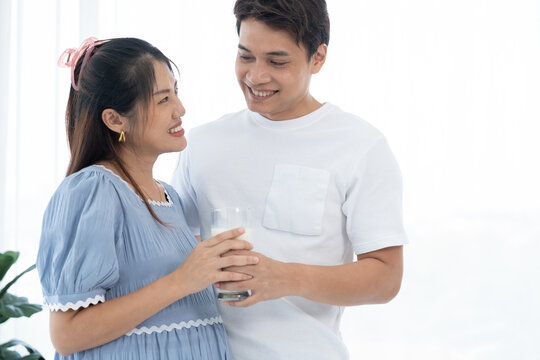 Husband caring for pregnant wife with fresh milk, highlighting family bonding, maternity care, love, and wellness in cozy indoor environment with natural daylight, lifestyle branding