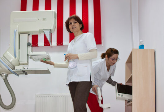 Radiologist cleaning mammography machine compression plate inside diagnostic clinic
