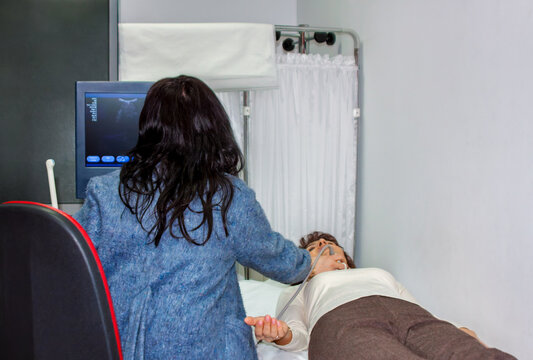 Doctor performing ultrasound examination on patient lying on hospital clinic bed