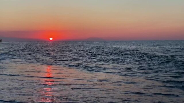 Horizontal shot of dramatic half sun dipping sunset on Bali beach