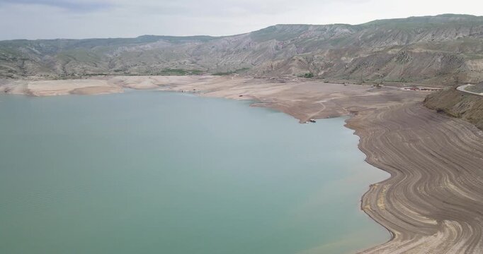 Cinematic aerial side fly shot of Chirkey reservoir with unique wave-like layered shoreline and mountain valley in Dagestan