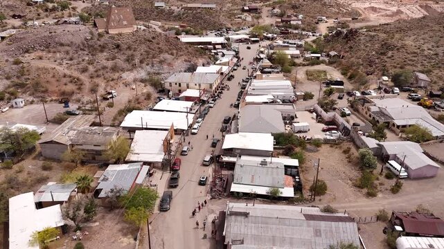 Scenic drone flyover of a rustic western settlement surrounded by rugged desert mountain peaks, Oatman, Arizona, USA