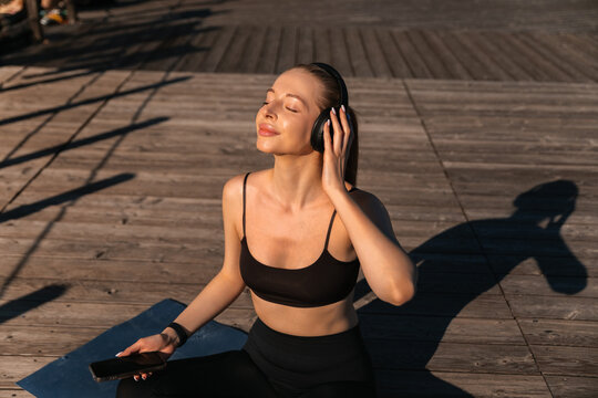 Woman enjoys music while exercising outdoors during morning sunlight