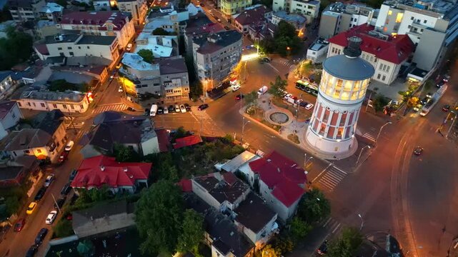 Cinematic high angle night view of the illuminated Bucharest fire tower in Romania. Iconic historic brick landmark surrounded by glowing city lights.