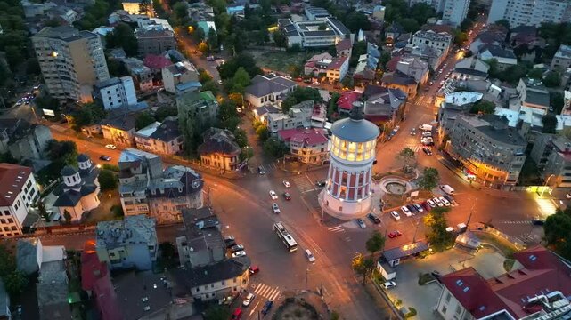 Cinematic high angle night view of the illuminated Bucharest fire tower in Romania. Iconic historic brick landmark surrounded by glowing city lights.