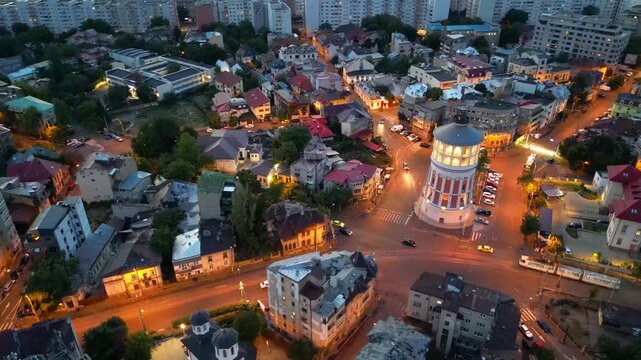 Cinematic high angle night view of the illuminated Bucharest fire tower in Romania. Iconic historic brick landmark surrounded by glowing city lights.