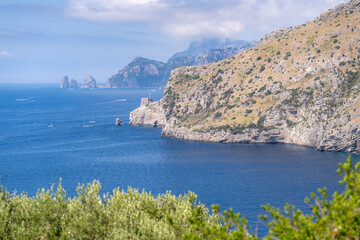 Fototapeta premium Stunning view of Ieranto Bay featuring distant Faraglioni rock formations near the island of Capri.