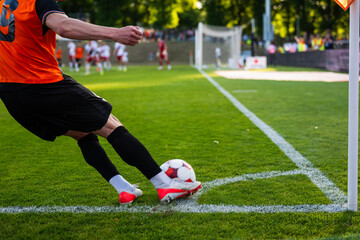 A soccer player kicking a ball from the corner line during a professional football match on a bright sunny day. © Dziurek
