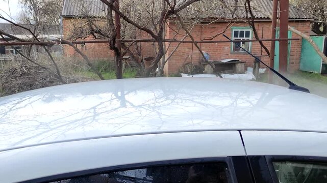 Washing white car with pressure washer, first person view