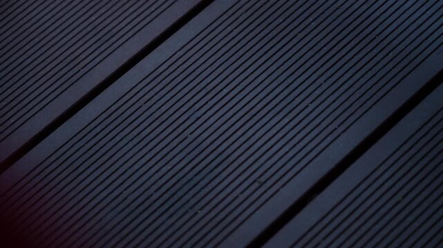 Close up cinematic footage of dark wooden decking boards with linear grooves and geometric patterns